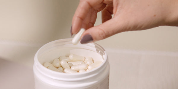 Hand greift nu3 L-Arginin Kapsel aus Kapseldose