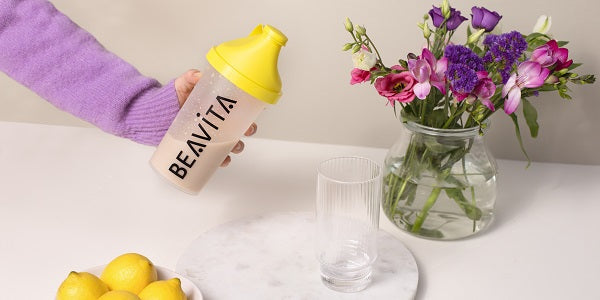 BEAVITA Slim Shaker mit Glas und Blumen auf dem Tisch