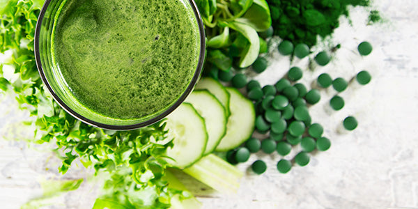 Chlorella-Drink im Glas und Tabletten mit Gurkenscheiben