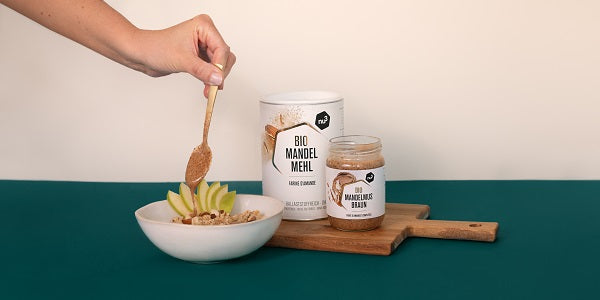 Frau gibt Mandelmus von nu3 in ihr Porridge
