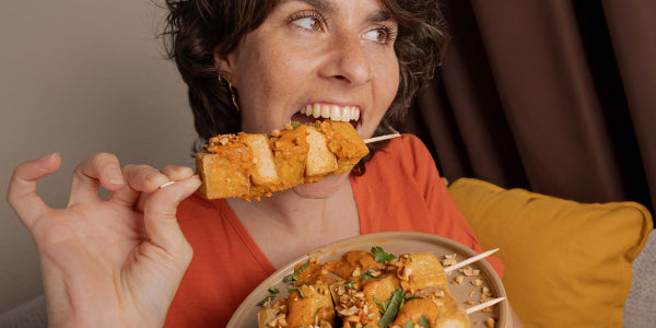 Frau, die in einen Tofu-Spieß beißt