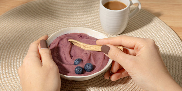 Hand hält Schüssel Frühstücks Acai Bowl mit Kaffe am Morgen nu3