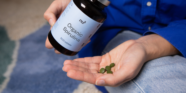 Hand hält Spirulina Kapseln