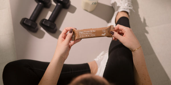 Sportliche Frau mit Vegan 3K Bar in der Hand