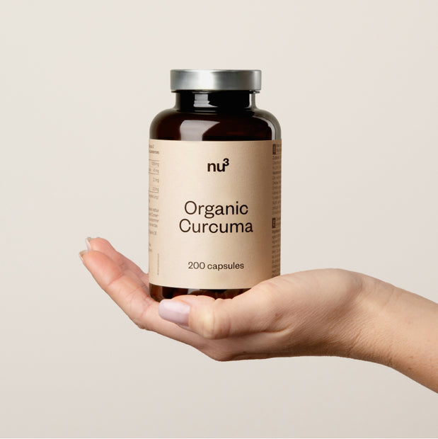 Hand mit einer Dose Kurkuma-Kapseln