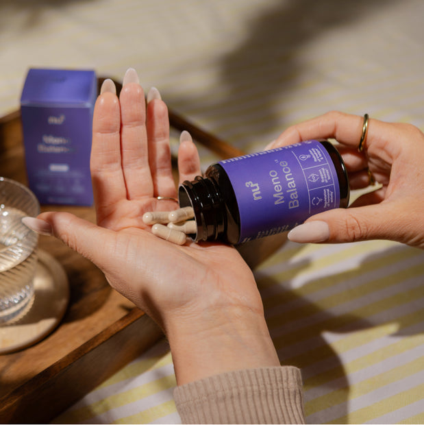 kapseln in der Hand mit einem Glas Wasser