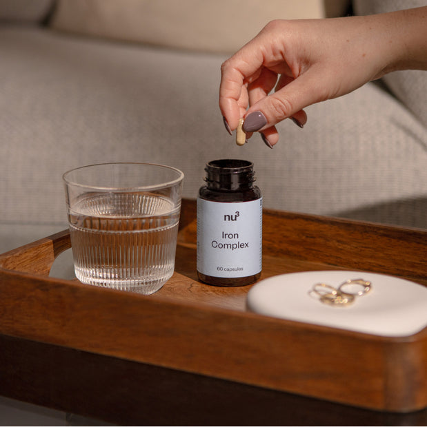 Dose mit Eisenkapseln & Wasser auf einem Tablett