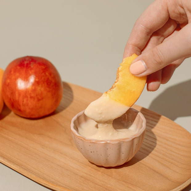 Hand hält Obst über Nussmus Dip