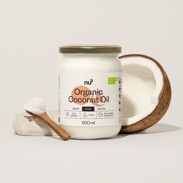 Kokosöl von nu3 neben Holzlöffel und Kokosnuss