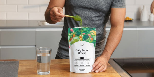 Greens Pulver mit Löffel und einem Glas Wasser