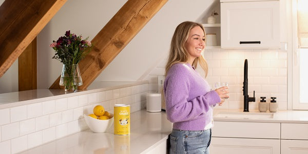 Person hält ein Glas mit BEAVITA Shake in der Küche