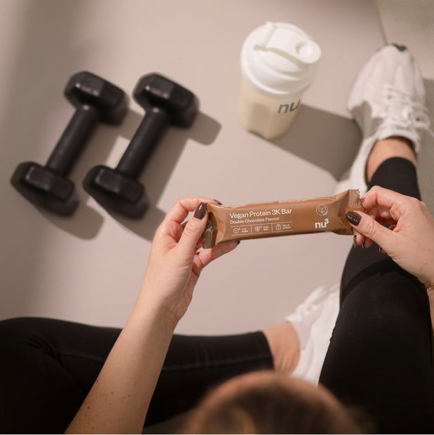 Sportliche Frau mit Vegan 3K Bar in der Hand