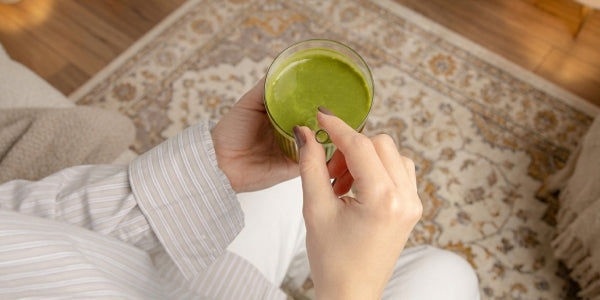Frau, die ein Glas mit Mindful Matcha Latte hält